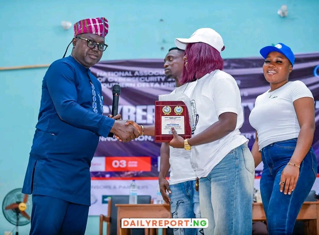 A university official shakes hands with the Eniebi Foundation representative while presenting the award plaque